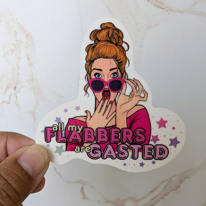 Sticker with a cartoon character and text held by a hand on a marble surface
