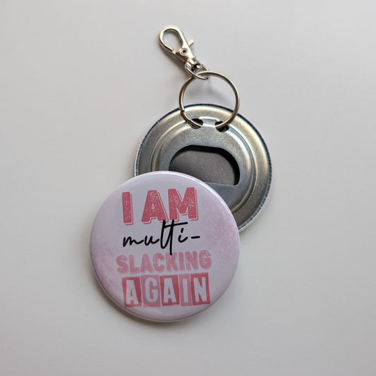 Keychain with bottle opener and 'I am multi-slacking again' text on a light gray background