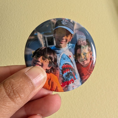 Button magnet with a printed image of three people on a yellow background