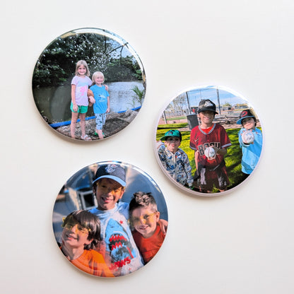 Three circular photo magnets with children's images on a white background