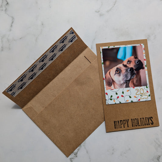 Kraft paper card with a dog photo magnet and 'Happy Holidays' text on a marble surface